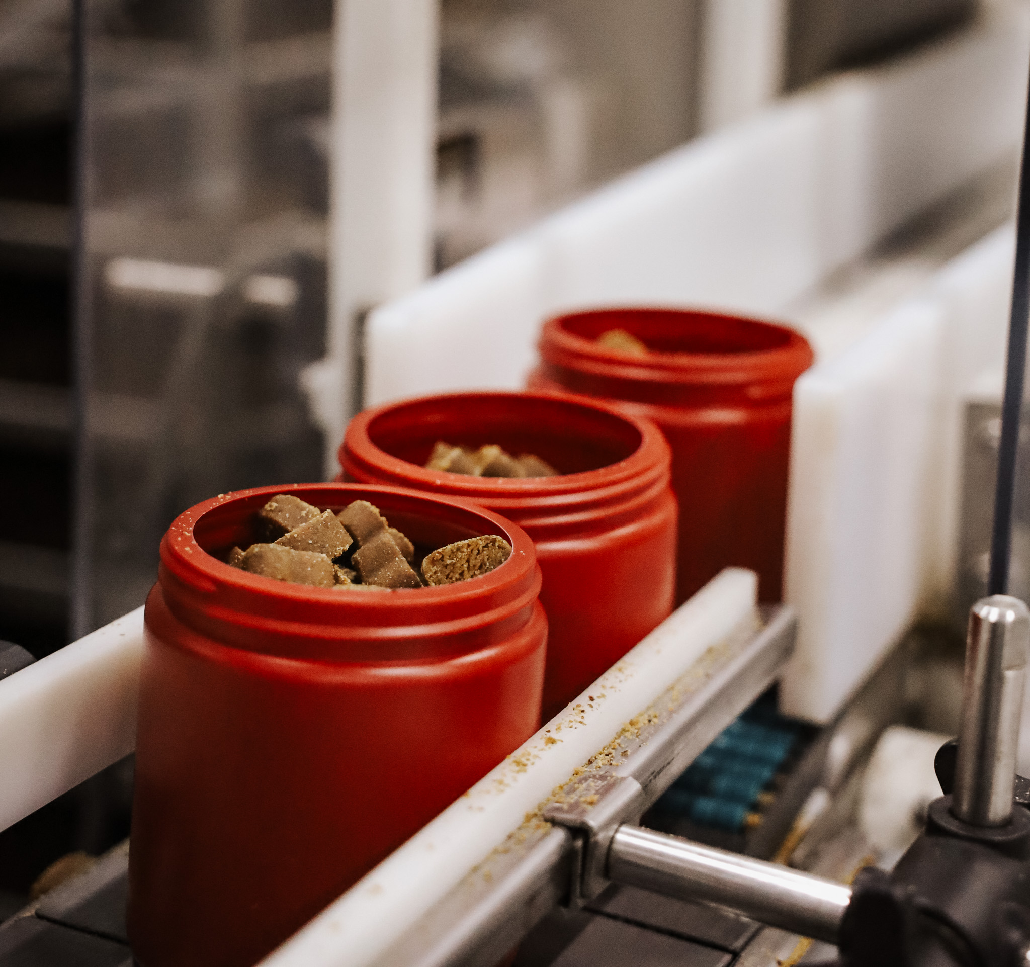 Close up of three red bottles on the conveyor belt